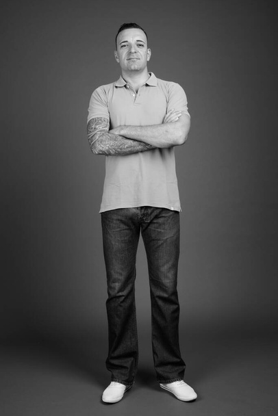 Studio záběr pohledný muž proti šedé pozadí v černé a bílé - Fotografie, Obrázek