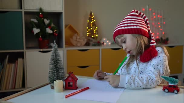 Маленька дівчинка в гномовому капелюсі пише листа Санті. - Кадри, відео