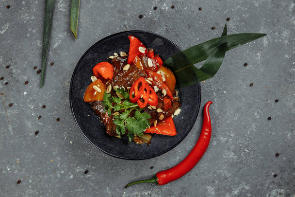 Beef wok. Traditional chinese mongolian beef stir fry in chinese cast iron wok with cooking chopsticks, stone slate background. Top view, copy space. - Photo, Image