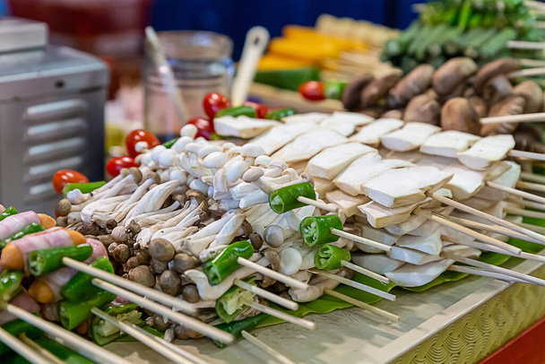 Brochetas de comida callejera asiática con ering y setas enoki en un pincho de bambú - Foto, imagen