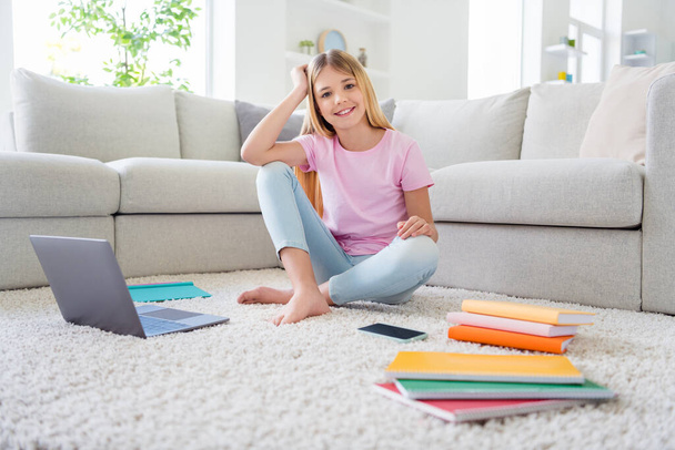 Full length photo of positive cheerful pupil kid sit floor carpet enjoy distance education study homeschool in house apartment indoors - Photo, image