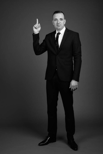 Studio shot di uomo d'affari che indossa tuta contro sfondo grigio in bianco e nero - Foto, immagini