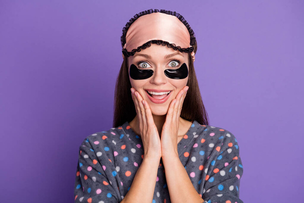 Photo of shocked surprised astonished girl touch hands face impressed weekend recreation healthy sleep news wear dotted pajama eye mask patches isolated over purple color background - Фото, зображення