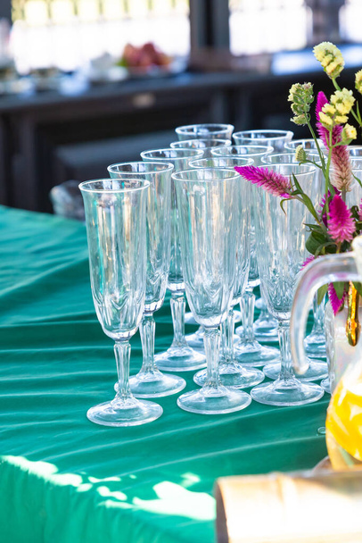 conjunto de taças de vinho longas fica em uma toalha de mesa verde em um fundo embaçado - Foto, Imagem