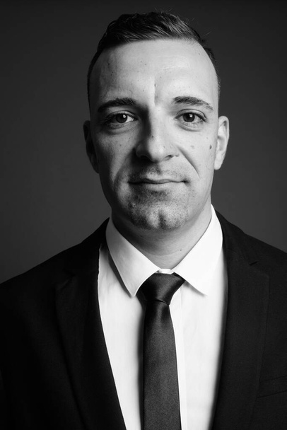Студійний знімок бізнесмена в костюмі на сірому фоні в чорно-білому
 - Фото, зображення