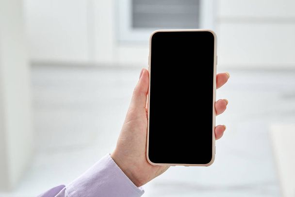 Close-up of the phone in the hands, on a light blurry background. - Photo, Image