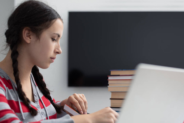 Social distancing student concept, education at home. High school girl doing homework at home with laptop. Teen study home the school is closed during Coronavirus Covid-19. - Φωτογραφία, εικόνα
