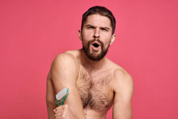 άνδρας με γυμνούς ώμους μασάζ σώματος φροντίδα του δέρματος ροζ φόντο - Φωτογραφία, εικόνα