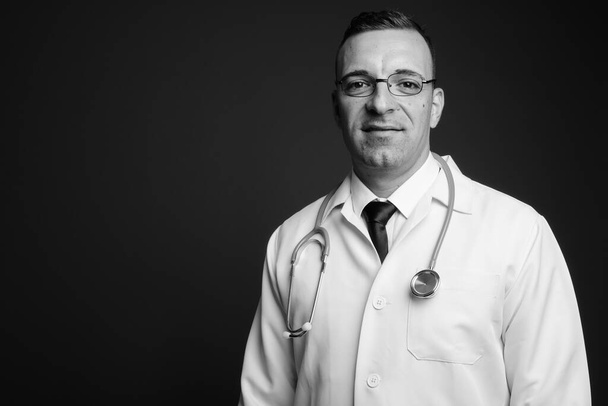 Estudio de hombre médico con gafas de vista sobre fondo gris en blanco y negro - Foto, Imagen