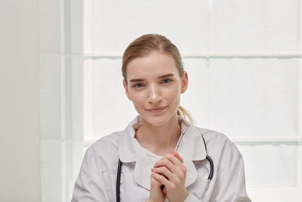 Portrait of a young cute female doctor in a white medical coat. White background - Photo, Image