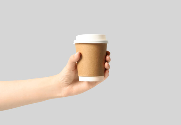 Woman holding takeaway paper coffee cup on light grey background, closeup - Photo, image