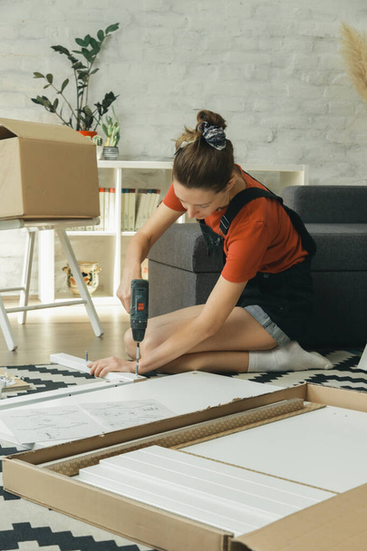 Blanke vrouw thuis monteren meubels door haarzelf - Foto, afbeelding
