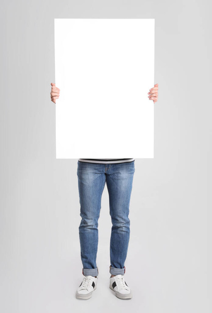Man holding blank poster on light grey background - Valokuva, kuva