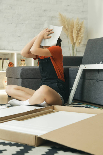 Annoyed woman having problem while assembling furniture by herself - Valokuva, kuva