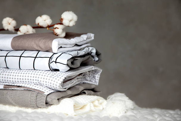 Stack of folded warm blankets with different design patterns and cotton branch on grey background. Knitted blankets. Production of natural plant-based textile fibers. Manufacture. Organic product - Foto, Bild