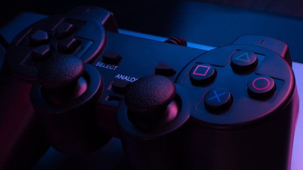 Controller di gioco sotto luci blu e rosse in una stanza buia - Foto, immagini