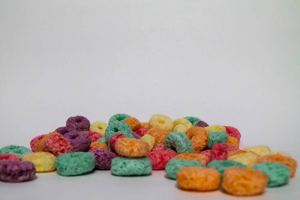 many fruit cereal wheels or froot loops of many colors scattered on a white background with room for text - Photo, Image
