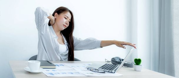Triste mujer de negocios asiática empleada infeliz trabajando con aburrido en el portátil y gráfico en la oficina cansado, concepto de síndrome de oficina. - Foto, Imagen