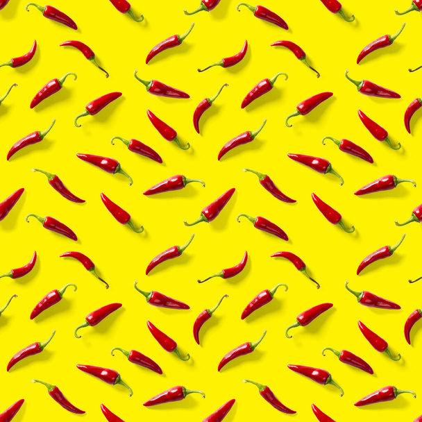 Red hot chilli seamless peppers pattern. Seamless pattern made of red chili or chilli on yellow background. Minimal food pattern. Food background. - 写真・画像