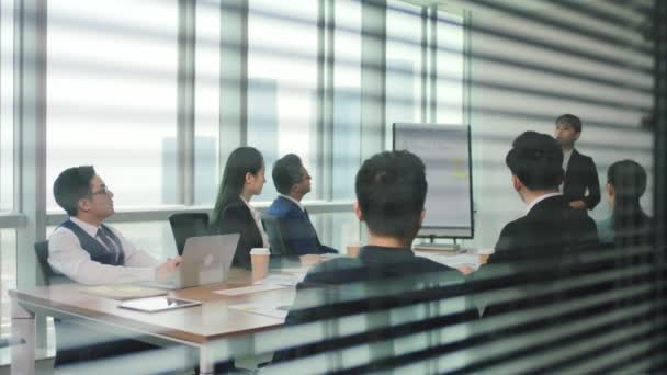 junior asian executive presenting business plan to team during staff meeting in modern office conference room - Footage, Video