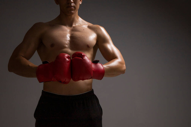 hombre sin camisa delante chocando con guantes de boxeo rojos - Foto, Imagen