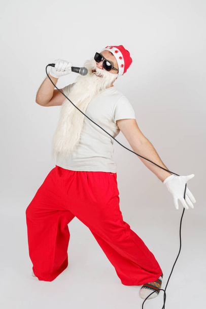 Holidays and christmas concept. Santa Claus sings with a microphone in his hand. Isolated on white - Fotografie, Obrázek