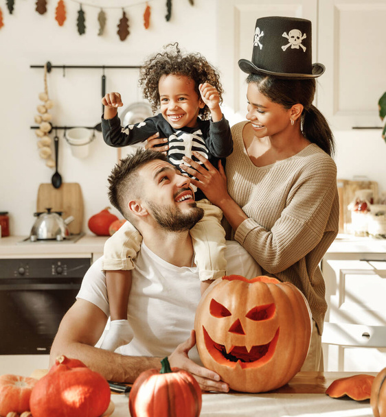 Mutlu çok ırklı aile anne, baba ve küçük oğul Cadılar Bayramı 'nı evde kutlayın. - Fotoğraf, Görsel