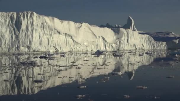 南極だ。鏡面反射の美しい青い氷山が外洋に浮かんでいます。背景には夕焼け空。雄大な冬の風景。旅行 - 映像、動画