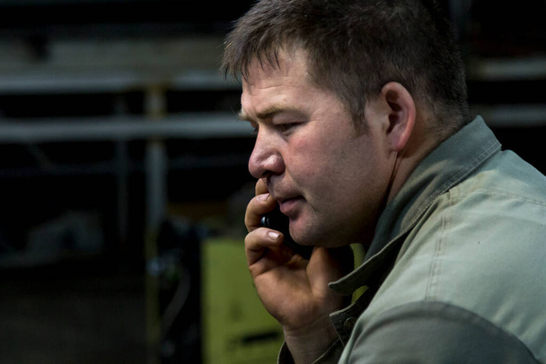 Portrait en gros plan d'un travailleur masculin sur son lieu de travail parlant sur son téléphone cellulaire - Photo, image