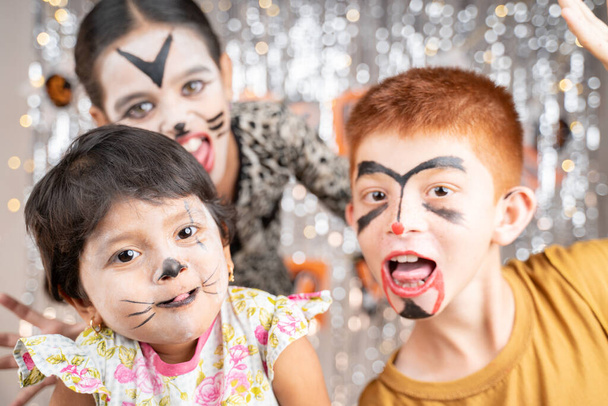 Groupe d'enfants en costumes d'Halloween gesticulant et faisant des visages effrayants ou effrayants sur fond décoré en regardant dans la caméra. - Photo, image