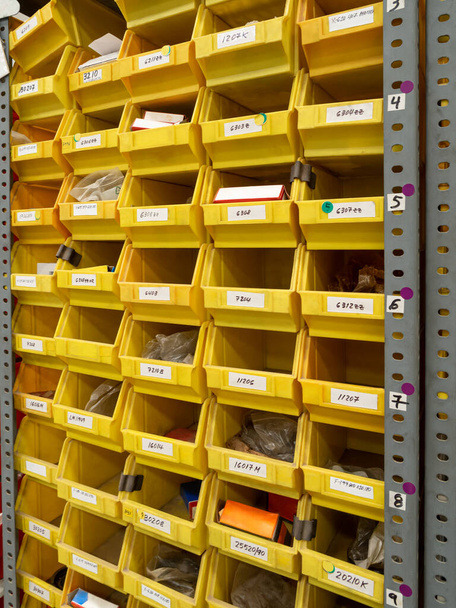 Оборудование для хранения. Многие желтые ящики на полках для хранения небольших инструментов и предметов дома, в гараже, в мастерской, на складе. Концепция склада. - Фото, изображение