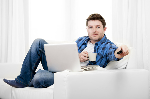 リラックスした男が自宅でコンピューターを使用してテレビのスイッチオン - 写真・画像
