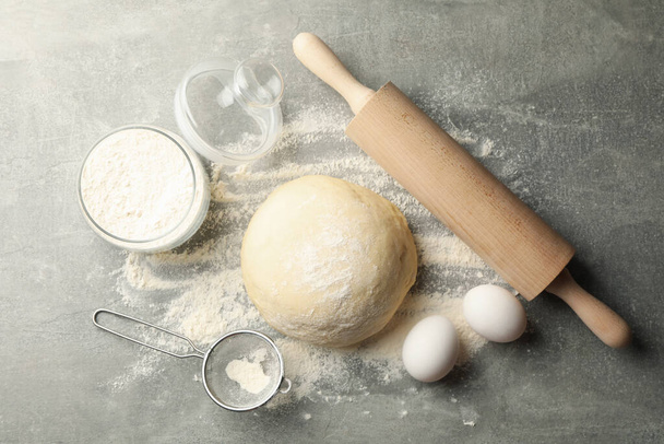 Concept for baking with dough on gray background - Foto, afbeelding