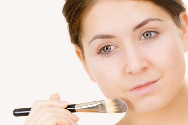 Young woman without makeup holds make up brush tool, ready to apply cosmetic foundation to her face. - Foto, Imagem