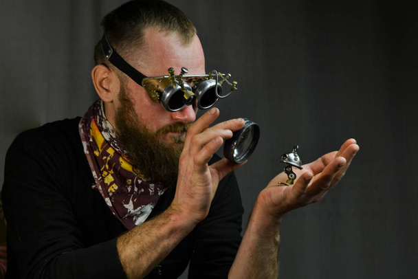 Стімпанк носить окуляри і тримає робота
 - Фото, зображення