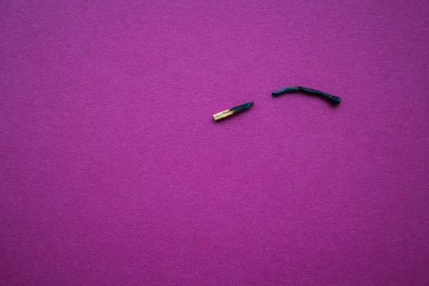 verbrande lucifer doormidden gebroken op een lila achtergrond - Foto, afbeelding