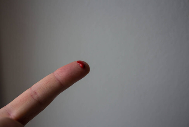 ein Tropfen rotes Blut an einem Finger - Foto, Bild