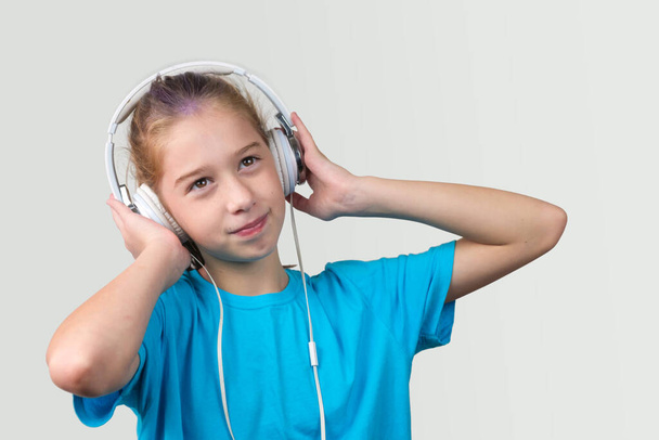 Egy barna szemű lány fülhallgatóval és zenét hallgatva. - Fotó, kép