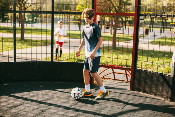 Un joven con uniforme deportivo entrena con una pelota en la cancha de fútbol estilo libre. Un jugador de fútbol juega con una pelota. Deportes, ocio, formación, freestyle - Foto, imagen