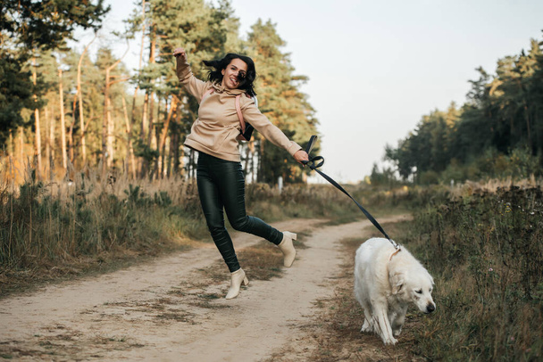 Girl with golden retriever dog walking on forest path - Fotografie, Obrázek