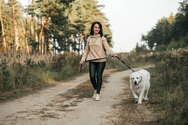 Girl with golden retriever dog walking on forest path - Фото, зображення