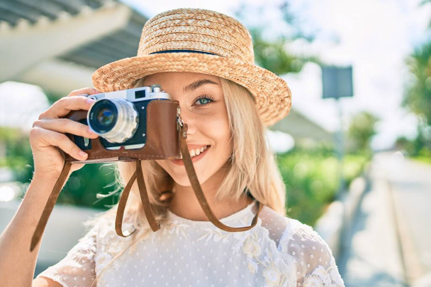 Young caucasian tourist girl smiling happy using vintage camera at street of city. - Foto, Bild