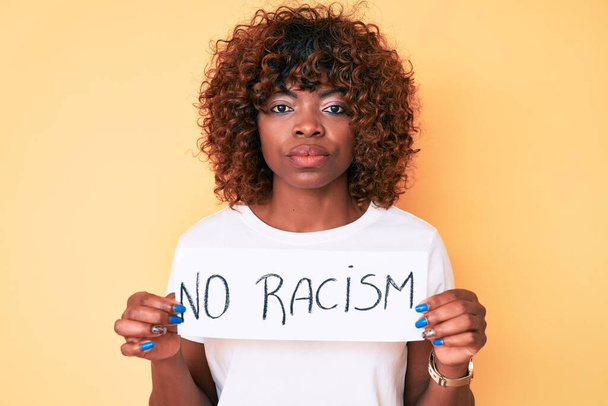 Mujer afroamericana joven que no sostiene ninguna actitud racista del pensamiento de la bandera y expresión sobria que mira confianza en sí mismo  - Foto, imagen