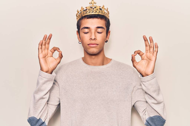 Молодий афроамериканський чоловік у корони принца розслабляється і посміхається очима, закритими роблячи медитаційний жест пальцями. йога концепція
.  - Фото, зображення