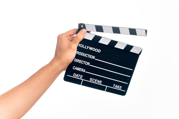 Χέρι καυκάσιου νέου κινηματογραφιστή που κρατά μια σανίδα πάνω από απομονωμένο λευκό φόντο - Φωτογραφία, εικόνα