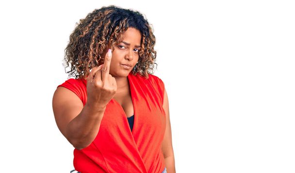 Молода афроамериканка плюс розмір жінка в повсякденному стилі з безрукою сорочкою, що показує середній палець, неввічливий і грубий хуй вираз
  - Фото, зображення