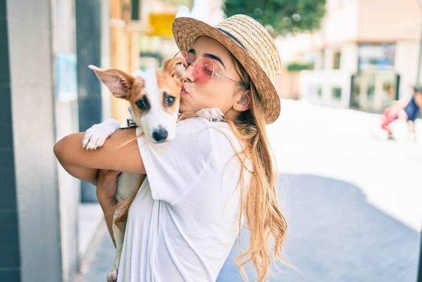 Sarışın, güzel bir kadın dışarıda yavru köpeğe sarılıp sarılıyor. - Fotoğraf, Görsel