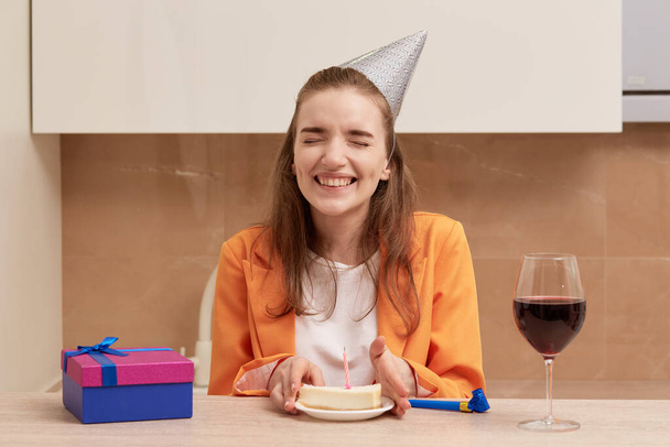 A young laughing woman holds a birthday cake in her hands. - Foto, imagen