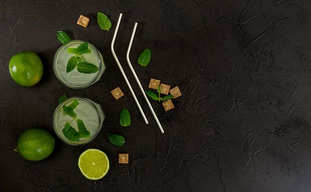 Vista dall'alto del rinfrescante cocktail alla menta alcolica mojito con rum e lime, bevanda fredda con accessori per barman  - Foto, immagini