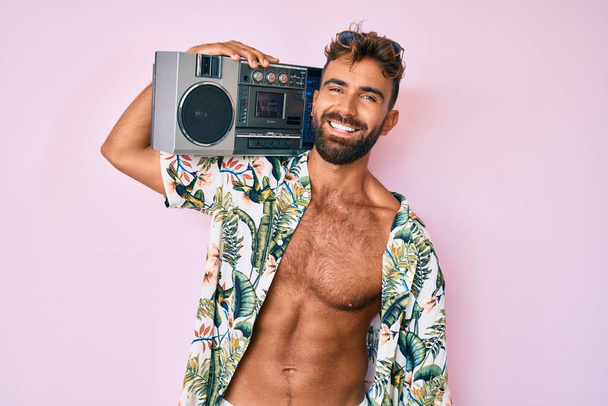 若いヒスパニック系の男性は夏の服を着て、ボムボックスを保持し、音楽の幸せな顔をカメラを見て腕を越え笑みを浮かべて聞く。正の人.  - 写真・画像